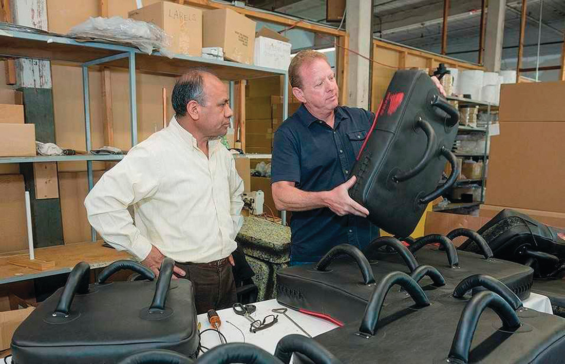 REINVENTING PROTECTION: Alejandro Batz and John Caito inspect riot gear manufactured at Amerisewn in Cranston. Caito designs the products, made from advanced composite materials and fabric to create gear that can withstand stabbing and slashing.